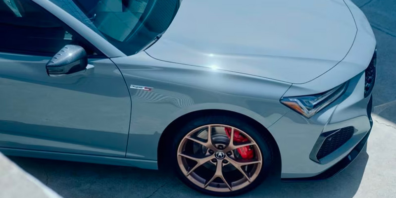 A sleek gray 2025 Acura TLX sedan with bronze wheels and red brake calipers, parked in sunlight.