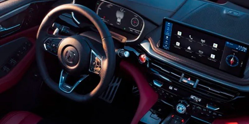 A modern 2025 Acura MDX dashboard with a steering wheel, touchscreen display, and red accents.