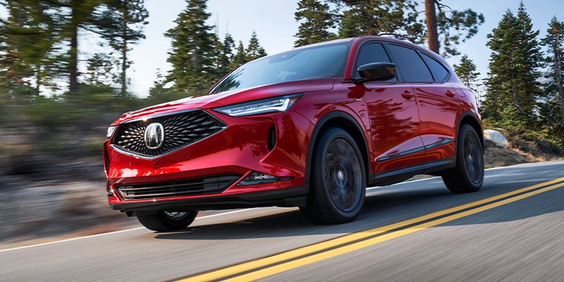 a red 2025 Acura MDX driving down a highway fast