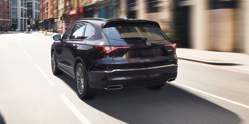 a rear view of a 2025 Acura MDX driving up a road